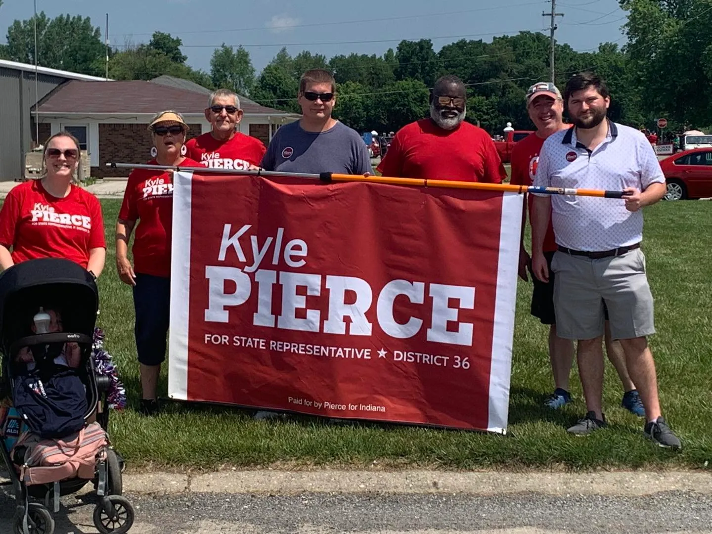 Team Pierce volunteers in red shirts carrying a Kyle Pierce for State Representative banner at a parade